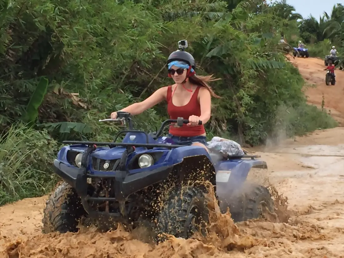 Solo rider on a quad splashing through a muddy trail in Koh Samui